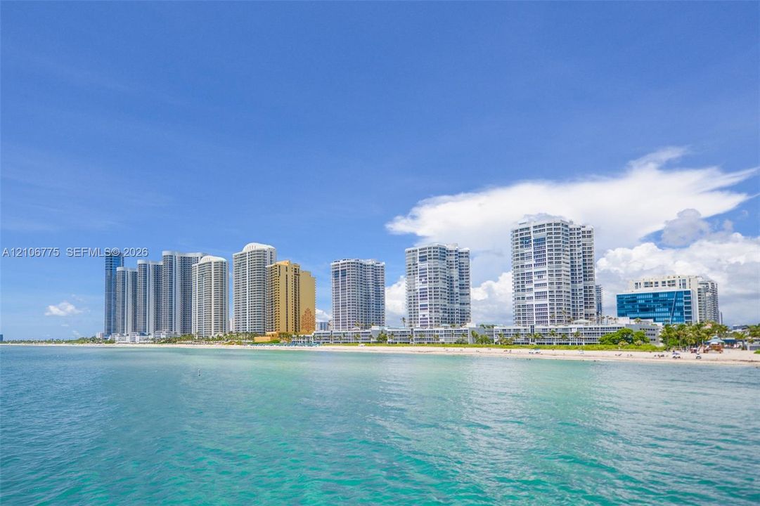 Direct oceanfront location featuring sandy coastline and proximity to high-rise metropolitan structures