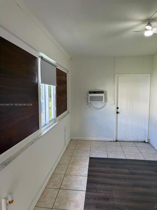 Interior space featuring wood-finish flooring, ceramic tile flooring, a mounted wall air conditioning unit, and a six-panel door