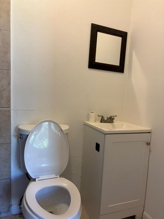Compact vanity featuring an integrated sink, dual-handle faucet, wall-mounted mirror, and tile wall accents