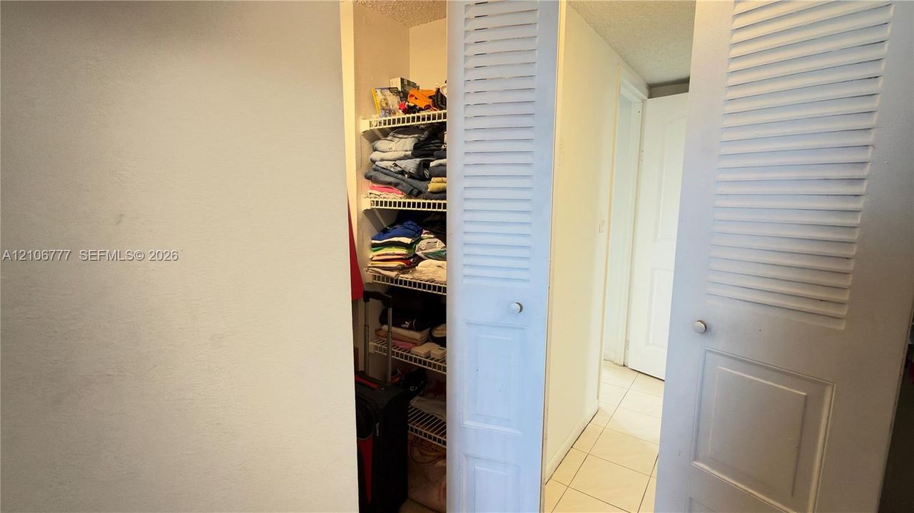 Storage closet featuring white louvered bifold doors and integrated wire shelving