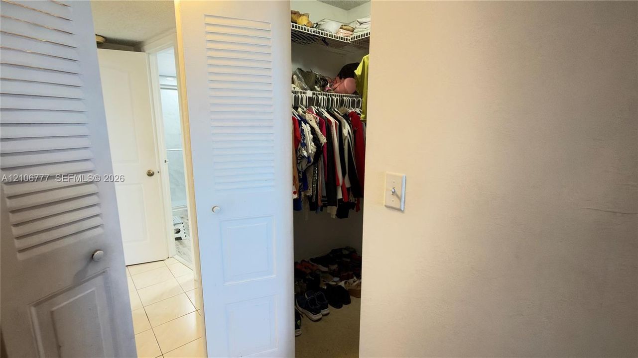 Storage area featuring louvered bi-fold doors, built-in wire shelving, and tiled flooring