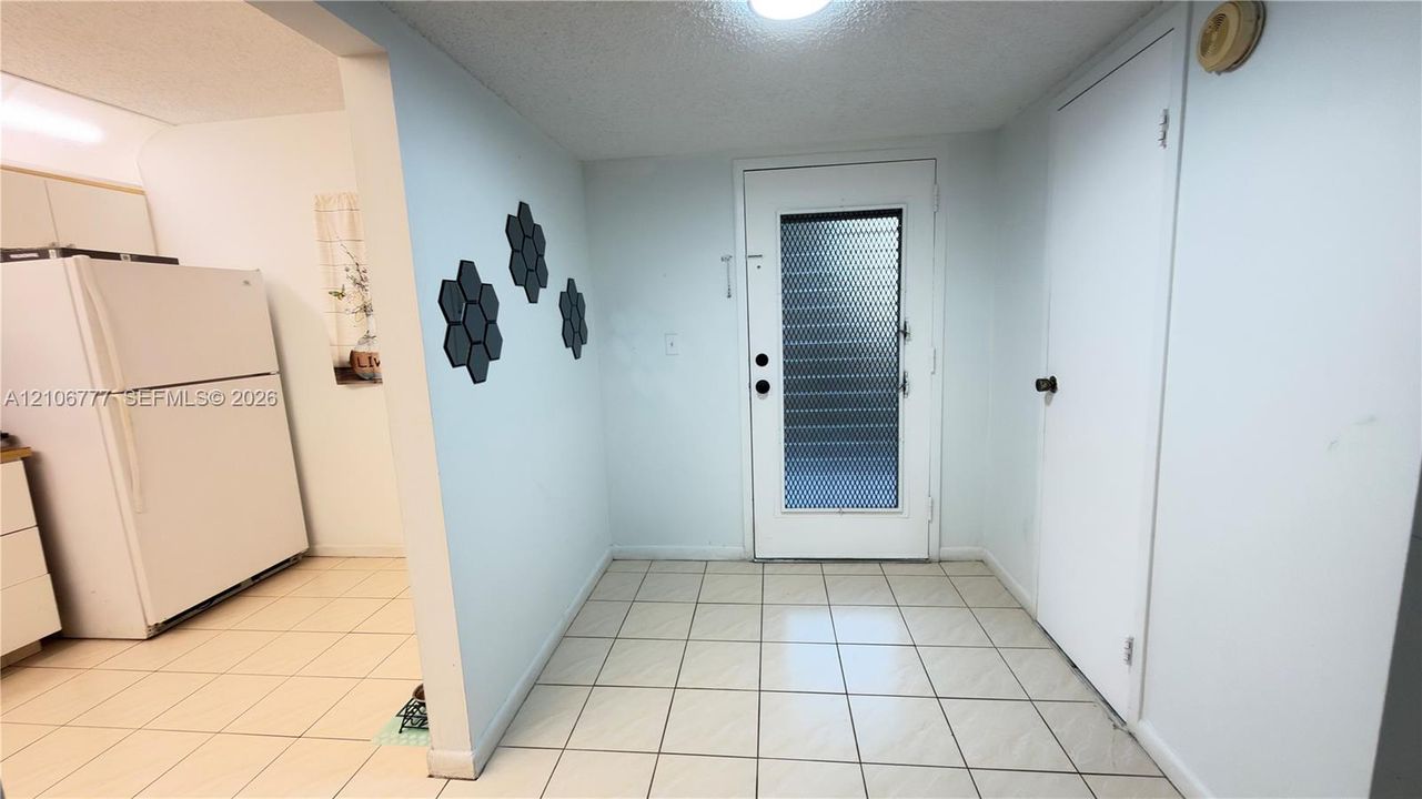 Entryway featuring white tile flooring, flush-mount ceiling lighting, and a glass-paneled exterior door