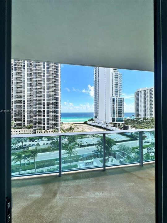 Concrete balcony with glass railing, offering ocean and urban scenery