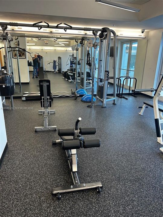 Fitness space featuring impact-resistant rubber flooring, floor-to-ceiling wall mirrors, and recessed lighting