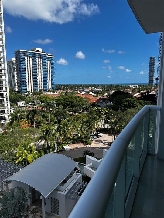 Private balcony featuring a glass-panel railing and expansive urban and ocean scenery