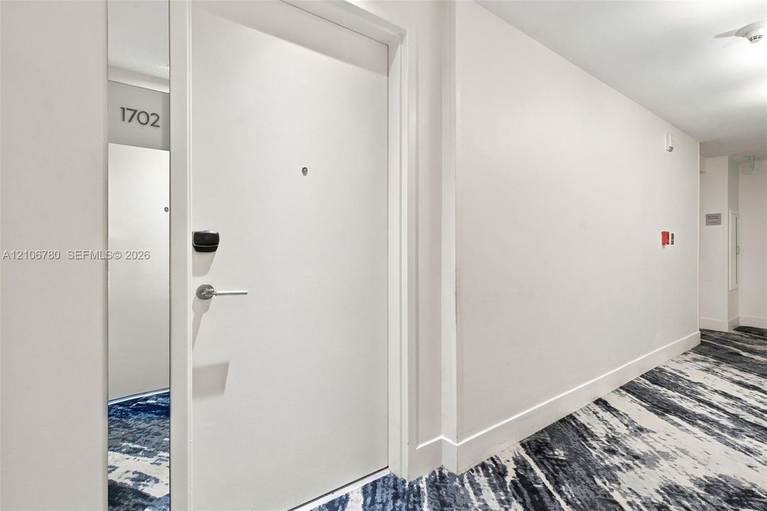 Solid core door with a matte silver lever handle, digital keypad entry, and integrated door viewer