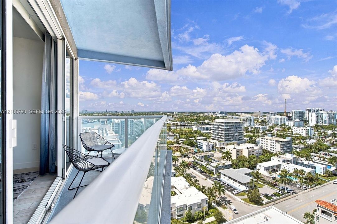 Covered balcony featuring glass railing and tile flooring