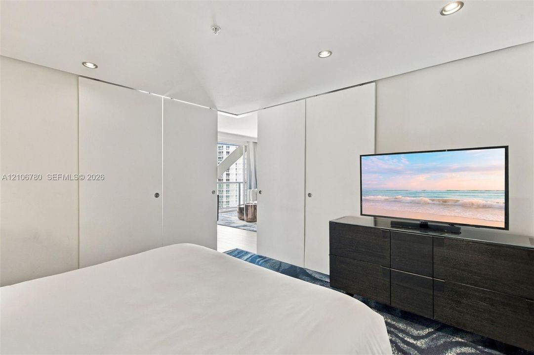 Floor-to-ceiling sliding panels, recessed lighting, and patterned floor covering