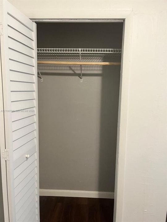 Closet featuring white louvered bi-fold doors, wire shelving, and a natural wood-finish hanging rod