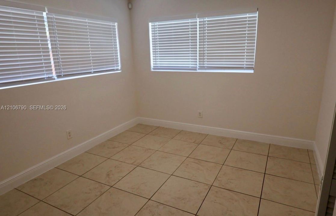 Neutral wall finishes, large-format tile flooring, and windows equipped with horizontal slat blinds