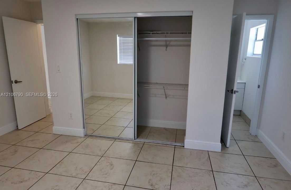 Room featuring ceramic tile flooring, a dual-paneled sliding mirrored closet door, and interior wire shelving