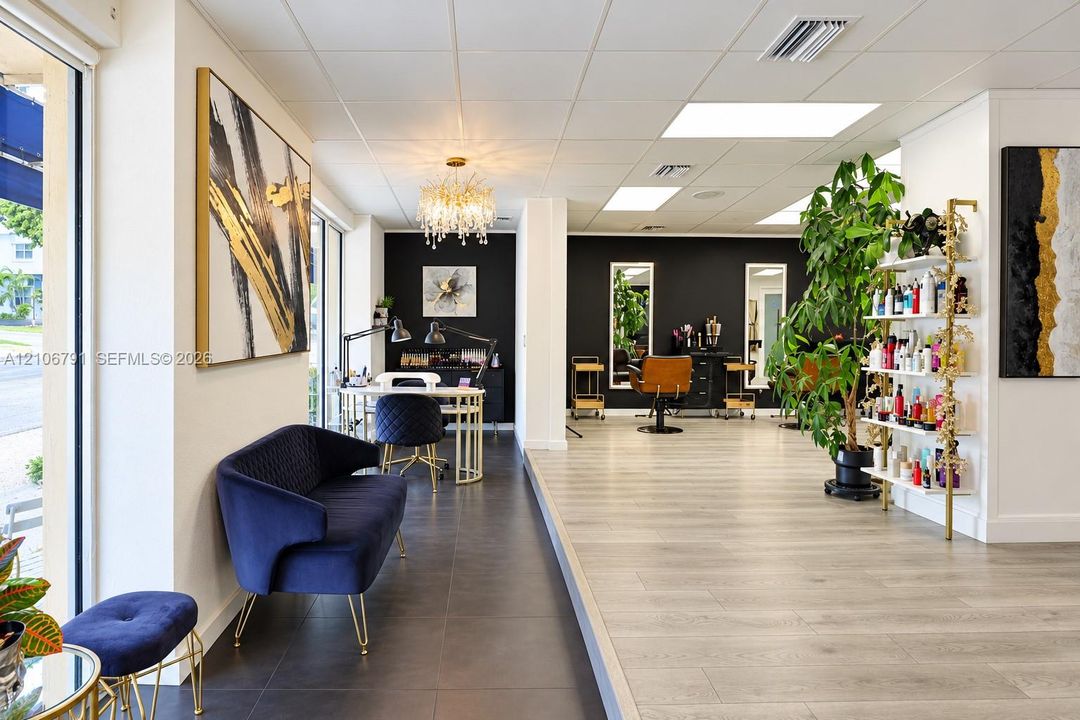 Open-concept commercial space featuring wood-finish flooring, large-format tile flooring, recessed ceiling lighting, and a crystal chandelier