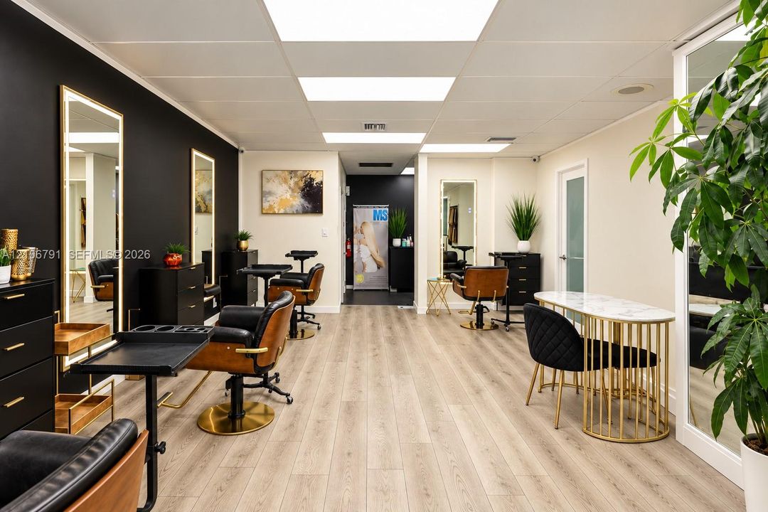 Open-concept interior featuring light wood-finish flooring, high-contrast matte black accent wall, integrated LED-lit vertical mirrors, and recessed ceiling lighting