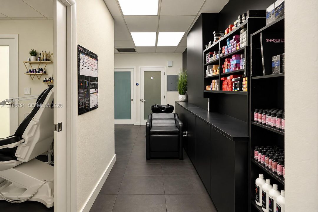 Custom matte black built-in cabinetry, large-format tile flooring, integrated shampoo station, recessed panel ceiling lighting, and dual frosted-glass interior doors