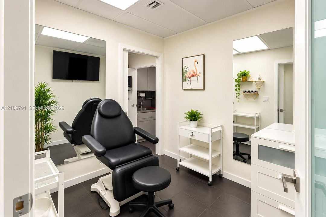 Room featuring dark tile flooring, two full-length wall-mounted mirrors, recessed ceiling lighting, and a built-in cabinet with a sink