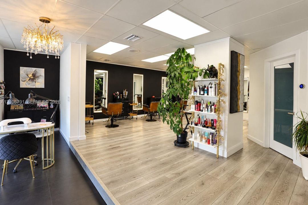 Interior space featuring wood-finish flooring, recessed lighting, a decorative crystal-style chandelier, wall-mounted mirrors, and an accent wall with high-contrast paint finish