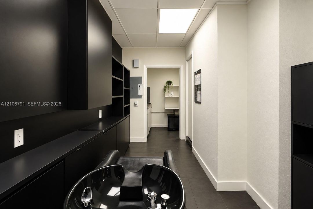 Matte black built-in cabinetry, dark-finish tile flooring, recessed square ceiling lighting, and a black ceramic basin with chrome fixtures