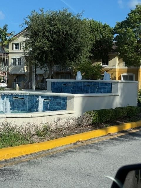 Tiered stone-finish water feature with blue mosaic tiling, integrated tiered fountain basins, and perimeter landscaping