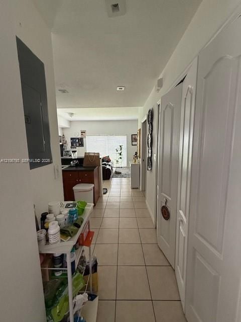 Hallway featuring light-colored tile flooring, multiple interior doors with arched-panel detailing, and recessed ceiling lighting
