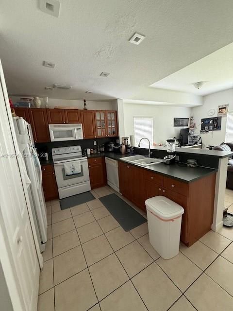 Kitchen featuring dark-toned cabinetry, solid surface countertops, recessed lighting, and tile flooring