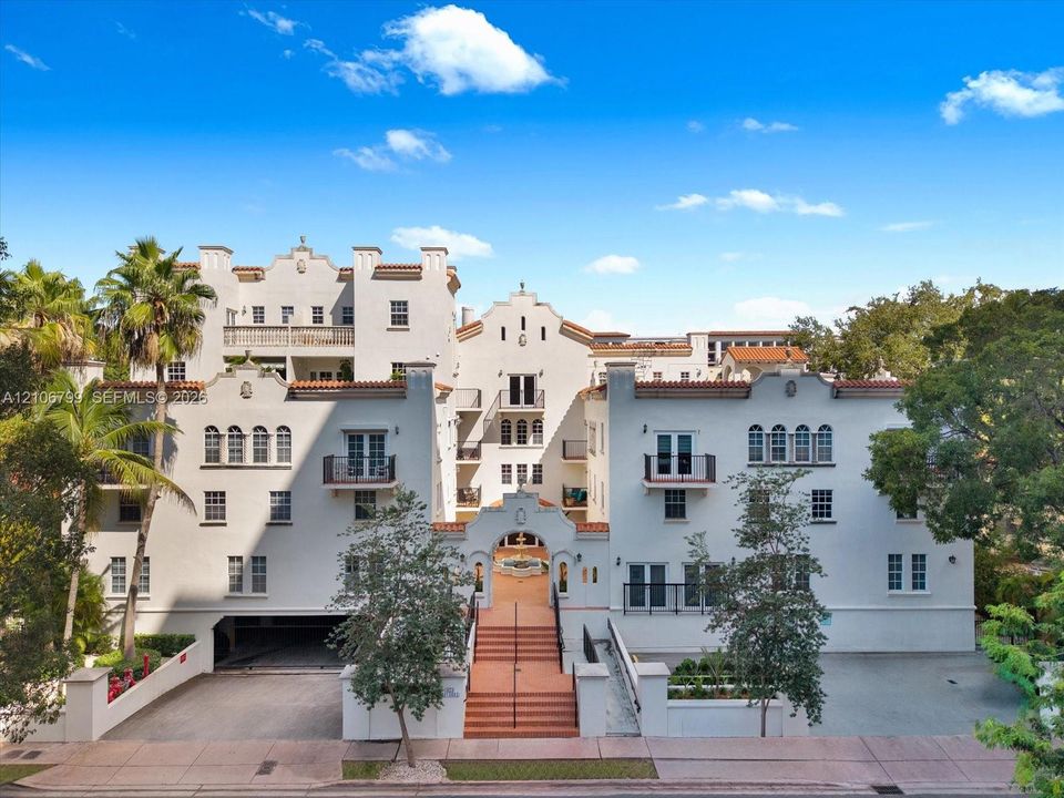 Spanish Colonial architecture featuring a stucco exterior, clay-tile roofing, arched entryway with a central fountain, and multi-level balconies