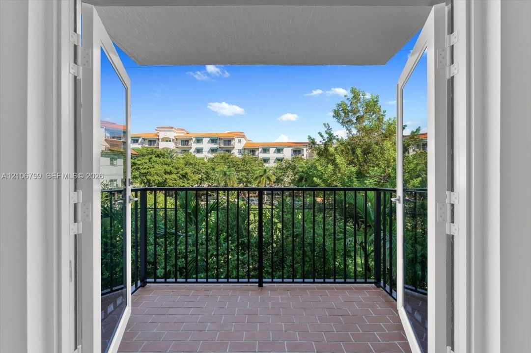 Balcony featuring double-pane glass doors, terracotta-style flooring, and a black metal railing