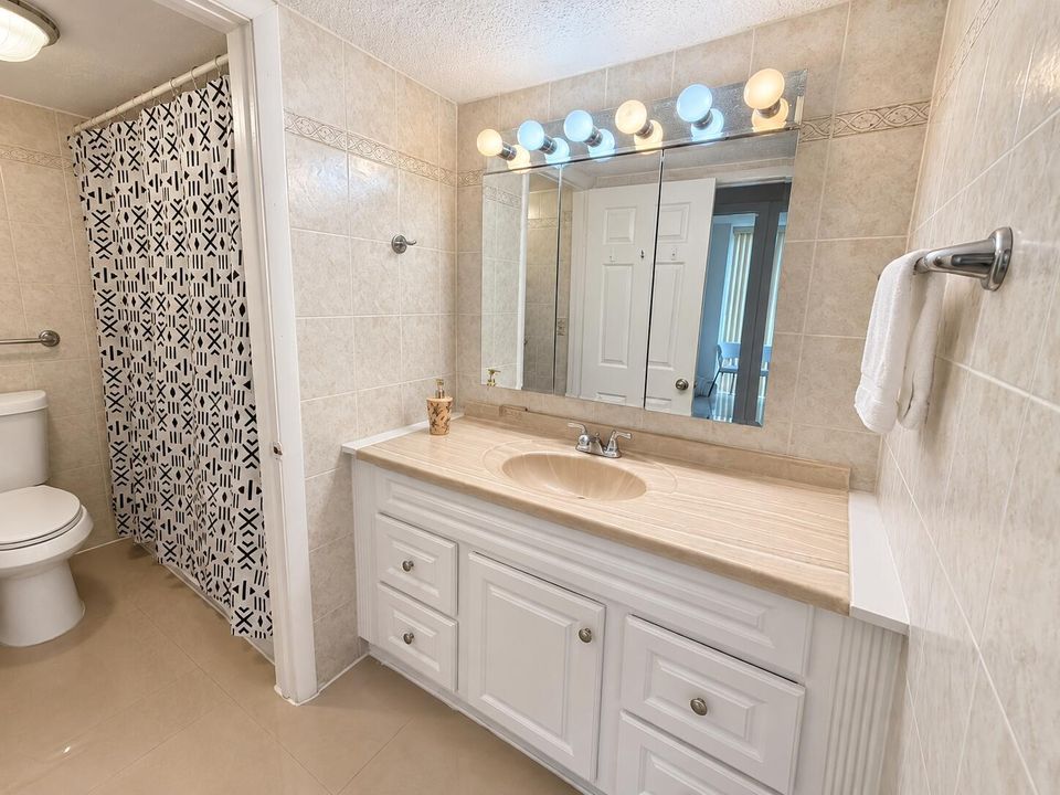 Baño beige renovado con espejo iluminad