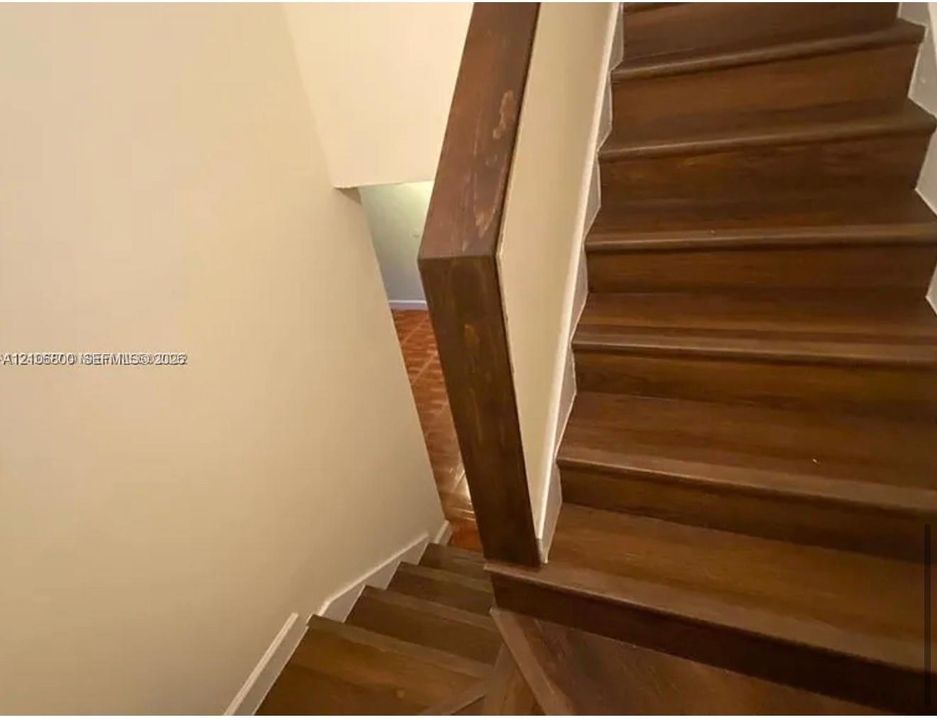 Staircase featuring wood-finish treads and a solid wood handrail