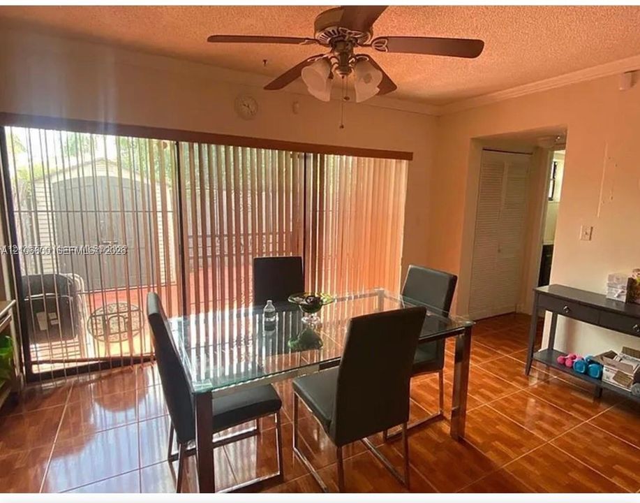 Ceramic tile flooring, multi-panel sliding glass door with vertical blinds, and a ceiling-mounted light fixture with fan