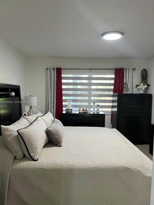Neutral wall color, dual-tone horizontal blinds, and a flush-mount overhead light fixture