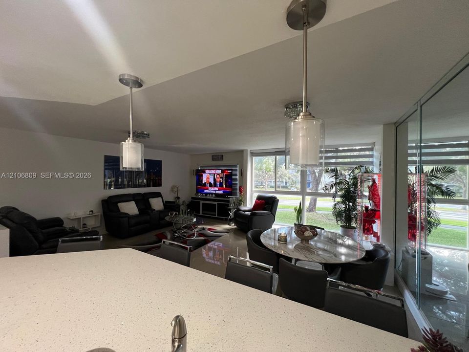 Quartz countertop with an integrated undermount sink, brushed nickel pendant lighting, high-gloss floor tile, and floor-to-ceiling windows