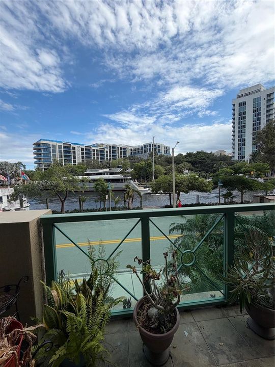 Balcony featuring green metal railing, tiled flooring, and exterior water scenery