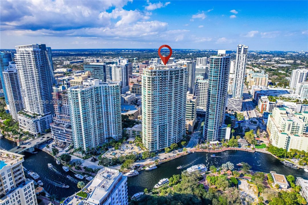 High-rise urban residence featuring floor-to-ceiling glass windows and a prominent waterfront location along a navigable canal