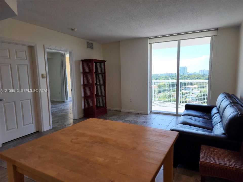 Interior living space featuring large-format tile flooring, floor-to-ceiling sliding glass doors, and a balcony with decorative metal railing