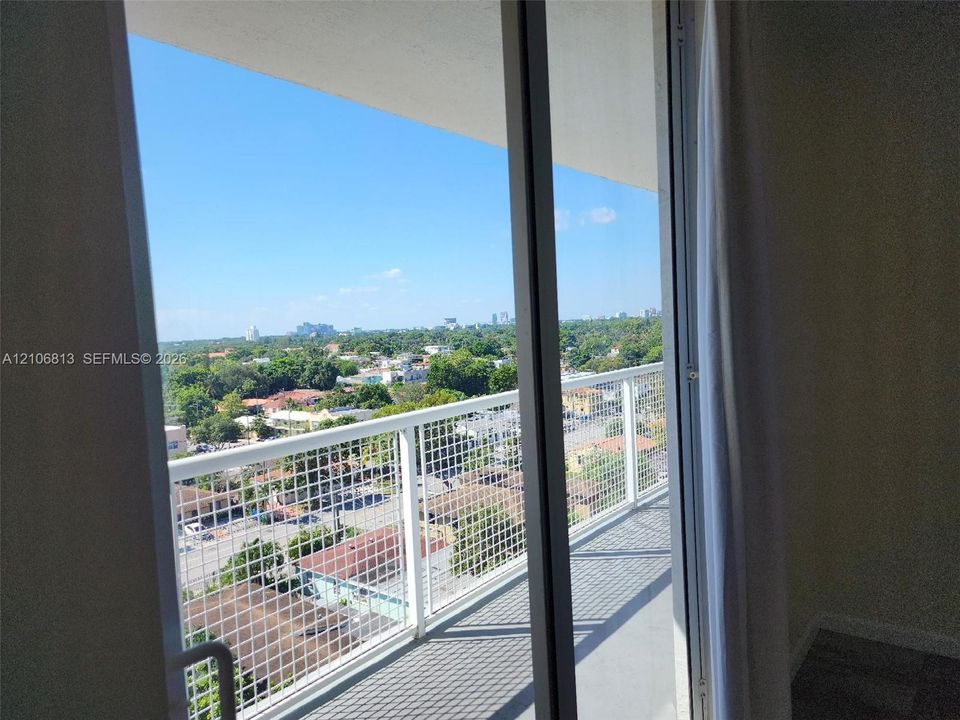 Private balcony featuring a white metal grid railing, sliding glass door, and exterior concrete flooring