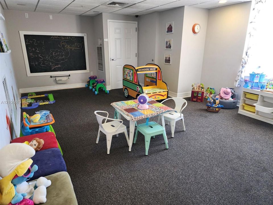 Multipurpose room featuring charcoal-toned carpeting, a built-in framed chalkboard, and neutral wall paint