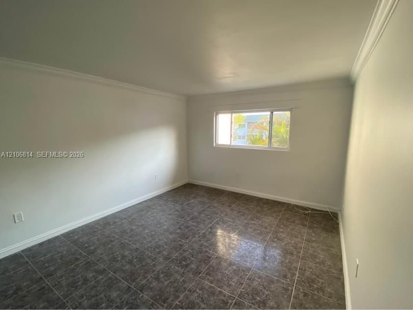 Neutral wall finishes, large-format tile flooring, crown molding, and a horizontal sliding window