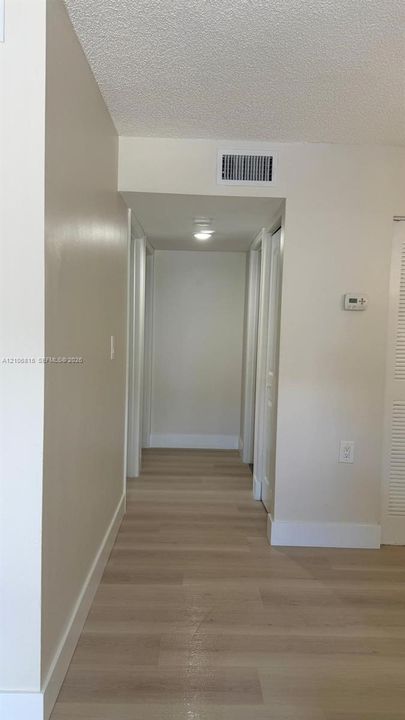 Interior hallway featuring wood-finish flooring, neutral wall paint, and ceiling-mounted light fixture