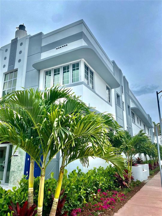 Art Deco architectural exterior featuring smooth stucco finish, tiered roofline, curved corner detail, and multi-lite windows