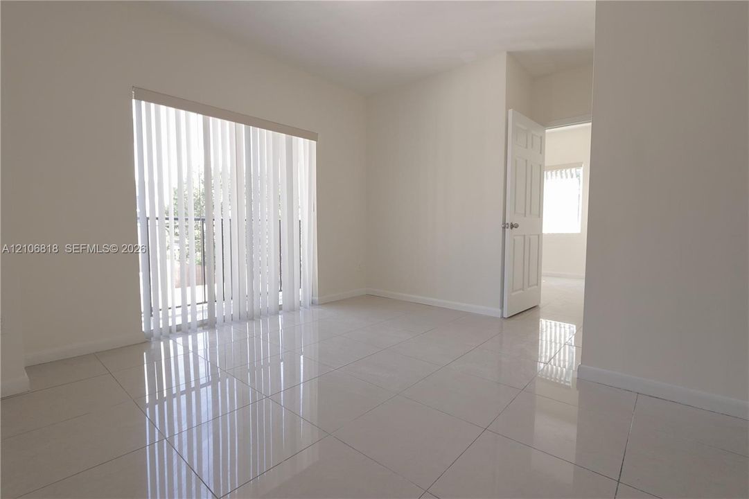 Neutral-toned room featuring large-format ceramic tile flooring, a glass sliding door, and a six-panel interior door