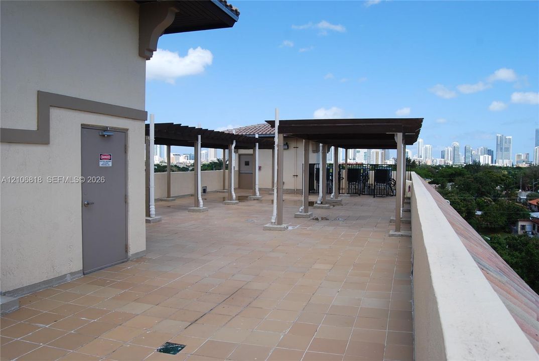 Rooftop terrace featuring tile flooring, wooden pergolas, and a perimeter wall