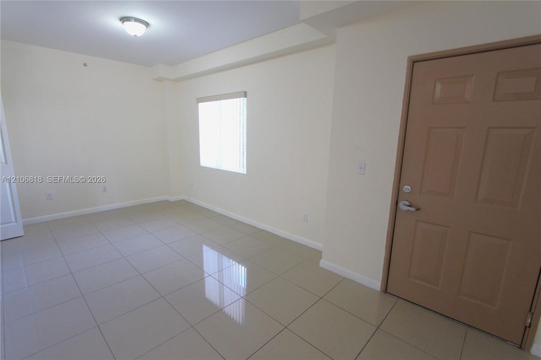 Neutral-toned ceramic tile flooring, solid-core interior door, and a flush-mount ceiling light fixture