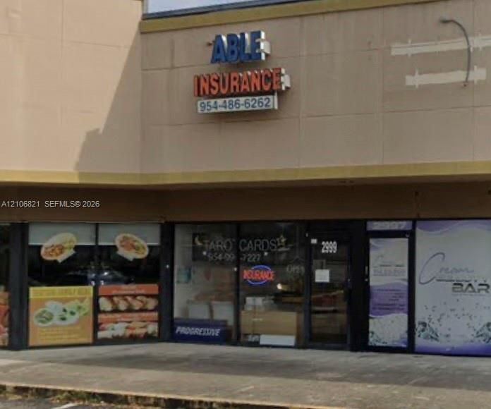 Commercial storefront featuring a flat facade with beige paneling, large-format glass display windows, and black metal framing