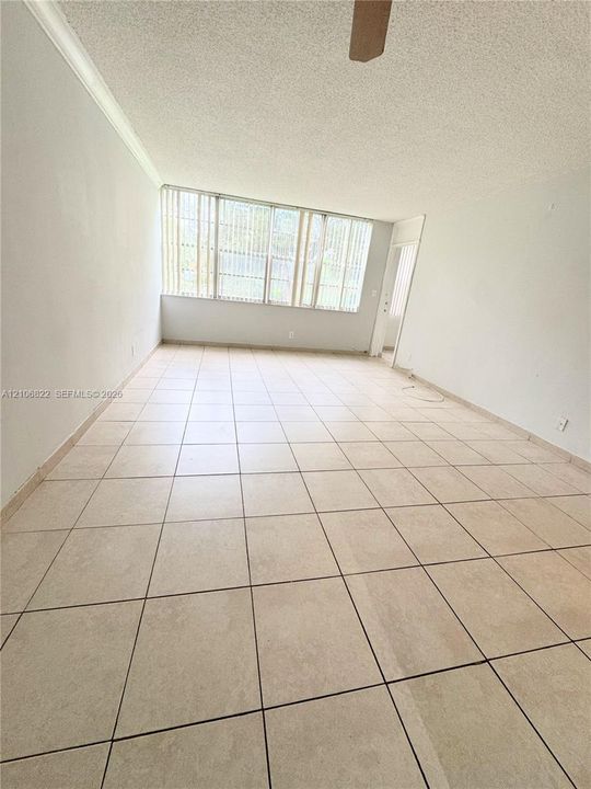 Interior space featuring large-format ceramic tile flooring, neutral walls, and extensive window groupings equipped with vertical blinds