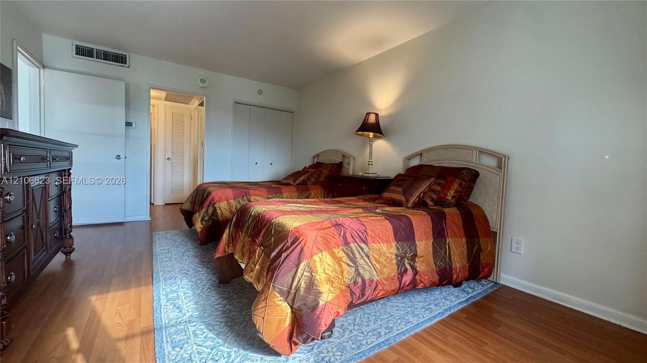 Room featuring wood-finish flooring, dual-panel closet doors, and recessed ceiling integration