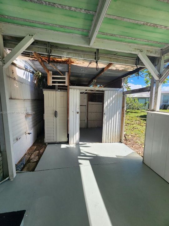 Covered outdoor space featuring a concrete floor, corrugated metal roofing, and built-in storage structures