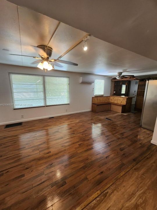 Wood-finish flooring, dual ceiling fans with integrated lighting, wall-mounted climate control unit, and built-in L-shaped bench seating