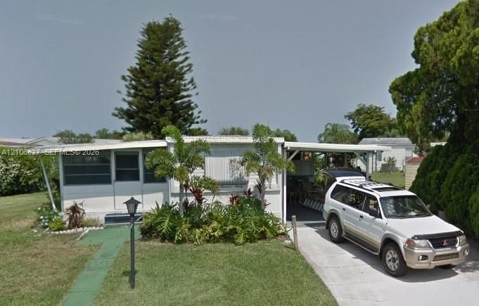 Single-story residence featuring light-colored siding, a covered carport, and a screened entry
