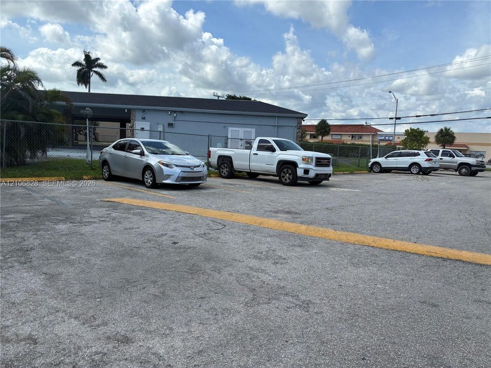 Asphalt-paved parking lot with designated yellow line striping and perimeter chain-link fencing