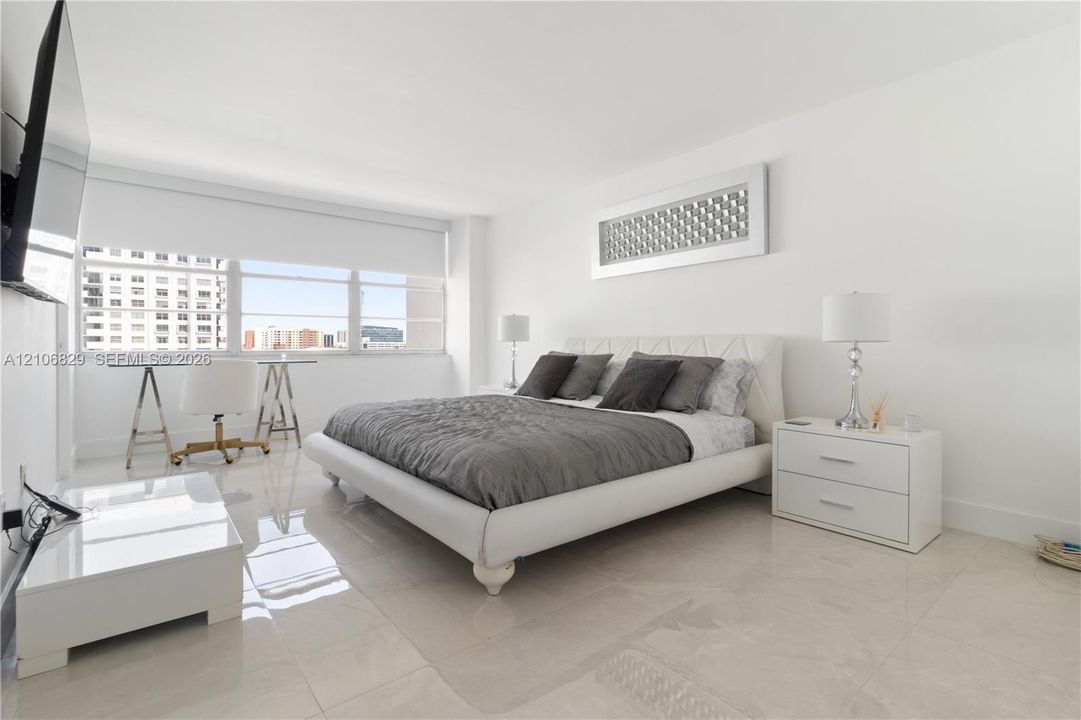 Neutral-toned tile flooring, oversized horizontal window with installed shade, and recessed lighting